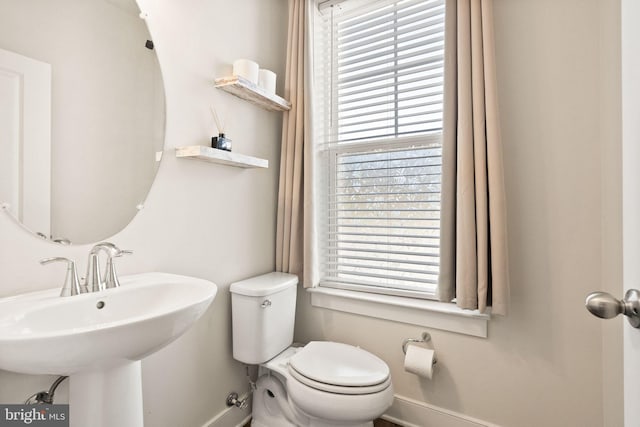 bathroom with toilet, a sink, a wealth of natural light, and baseboards