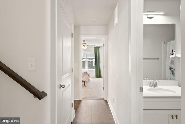 hall with baseboards, a sink, and wood finished floors