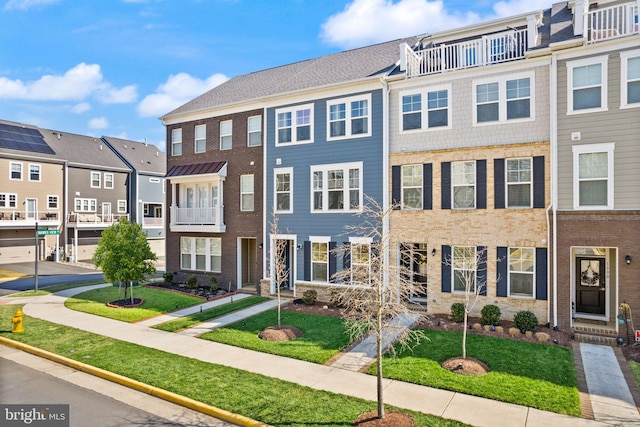 multi unit property featuring a residential view, brick siding, and a front yard