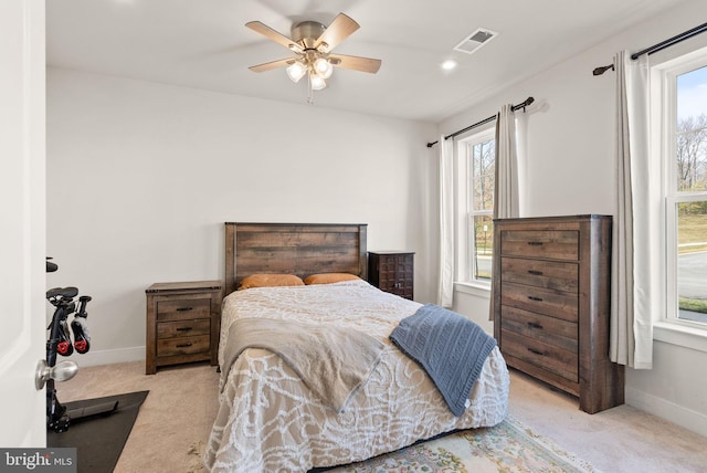 carpeted bedroom with ceiling fan, multiple windows, visible vents, and baseboards