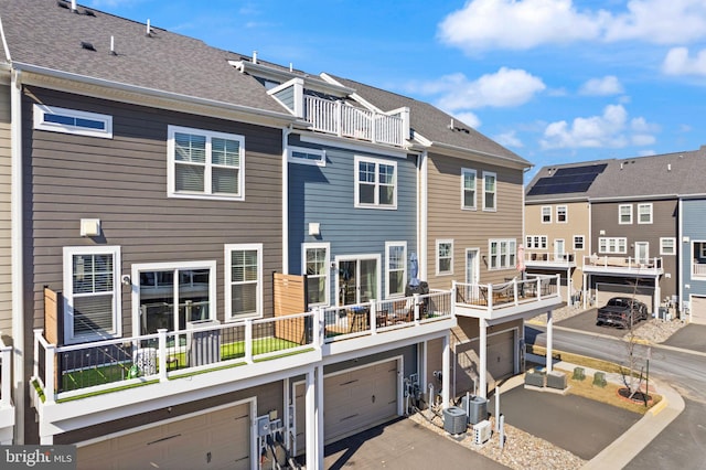 rear view of property featuring a shingled roof, cooling unit, and a residential view