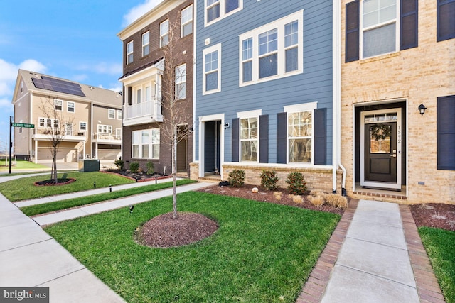 townhome / multi-family property with a front lawn and brick siding