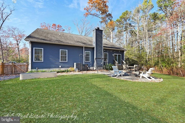 rear view of property with a fire pit, a patio area, a yard, and central air condition unit