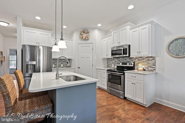 kitchen with white cabinets, sink, appliances with stainless steel finishes, and an island with sink