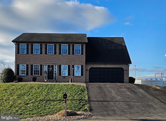 colonial inspired home with a front lawn and a garage