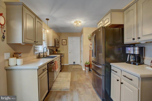 kitchen with sink, light hardwood / wood-style flooring, decorative light fixtures, cream cabinetry, and appliances with stainless steel finishes