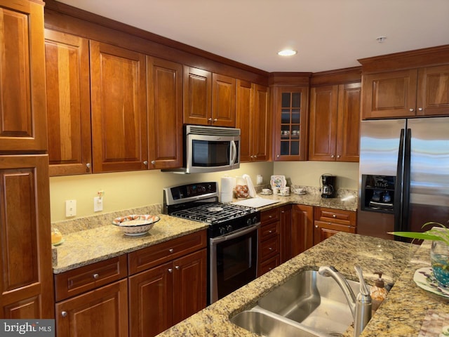 kitchen featuring light stone counters, sink, and appliances with stainless steel finishes