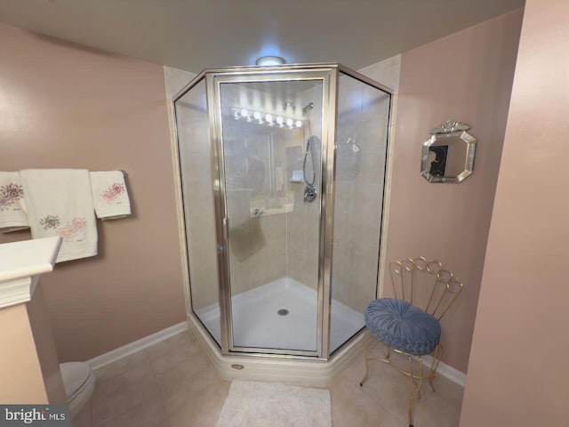 bathroom featuring tile patterned floors, toilet, and a shower with shower door