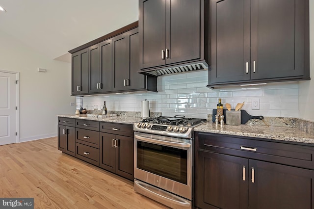 kitchen with tasteful backsplash, light stone counters, dark brown cabinetry, stainless steel gas stove, and light hardwood / wood-style floors