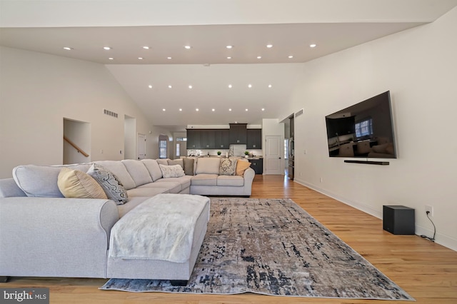 living room featuring light wood-type flooring and high vaulted ceiling