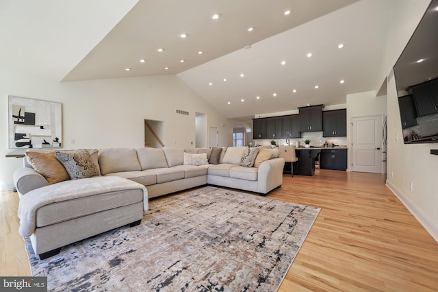 living room with light wood-type flooring and high vaulted ceiling