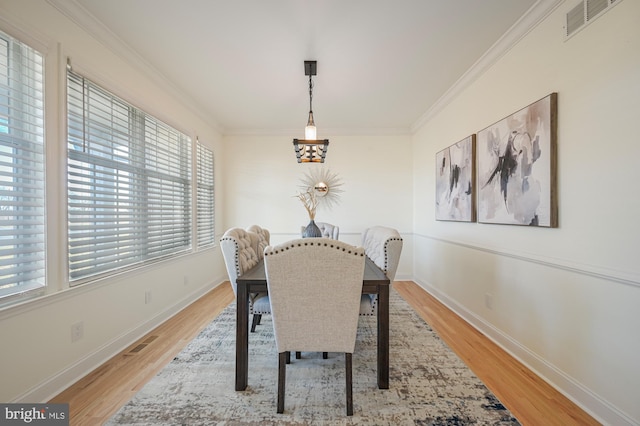 dining room with light wood-type flooring and ornamental molding