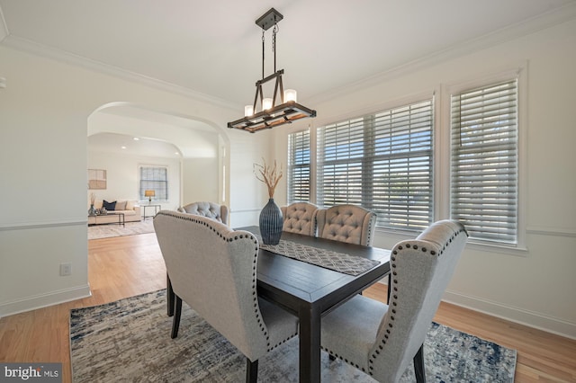 dining area featuring hardwood / wood-style floors, crown molding, and an inviting chandelier