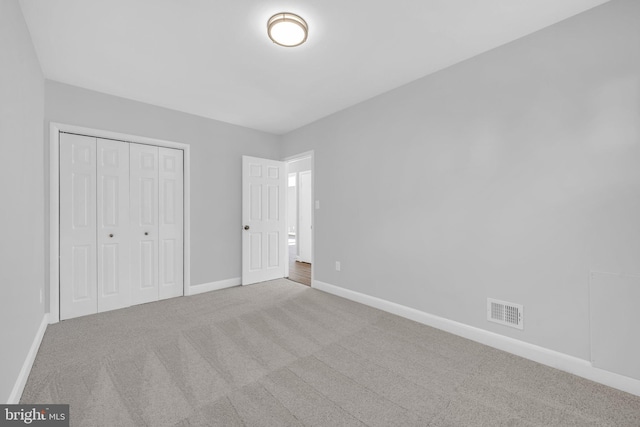 unfurnished bedroom with a closet and light colored carpet