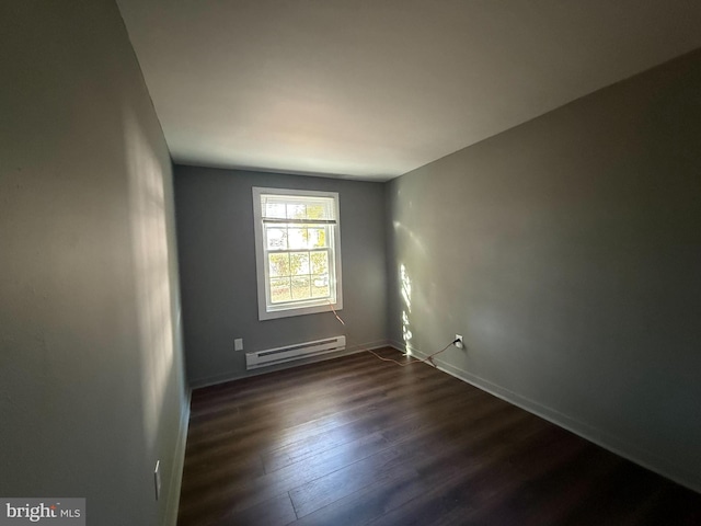 unfurnished room featuring a baseboard heating unit and dark wood-type flooring