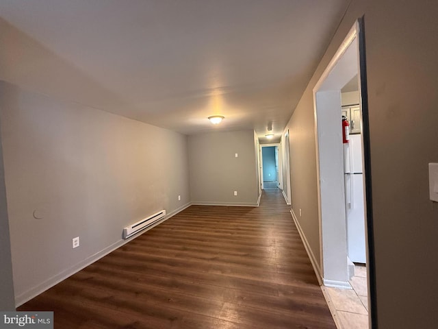 empty room featuring dark hardwood / wood-style flooring and a baseboard radiator