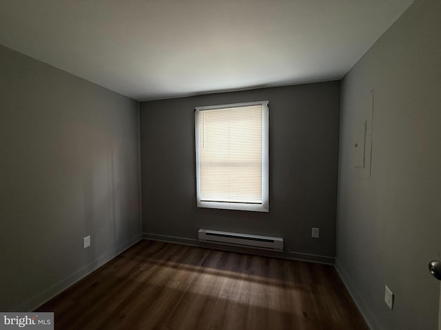 spare room with dark hardwood / wood-style floors and a baseboard heating unit