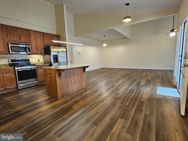 kitchen with a breakfast bar, appliances with stainless steel finishes, high vaulted ceiling, and a kitchen island