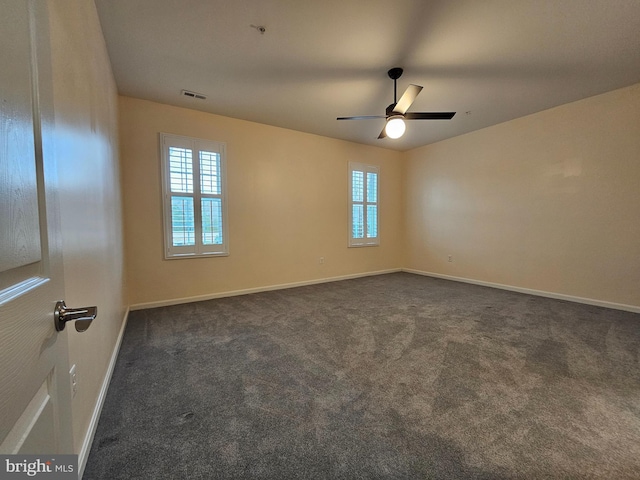 unfurnished room with dark colored carpet and ceiling fan