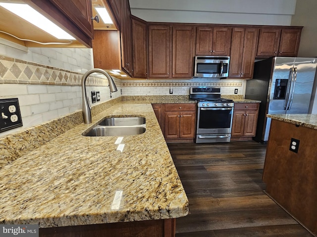 kitchen with dark hardwood / wood-style flooring, sink, light stone countertops, and stainless steel appliances