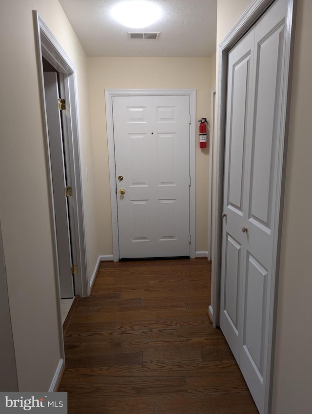 doorway with dark hardwood / wood-style flooring and a textured ceiling