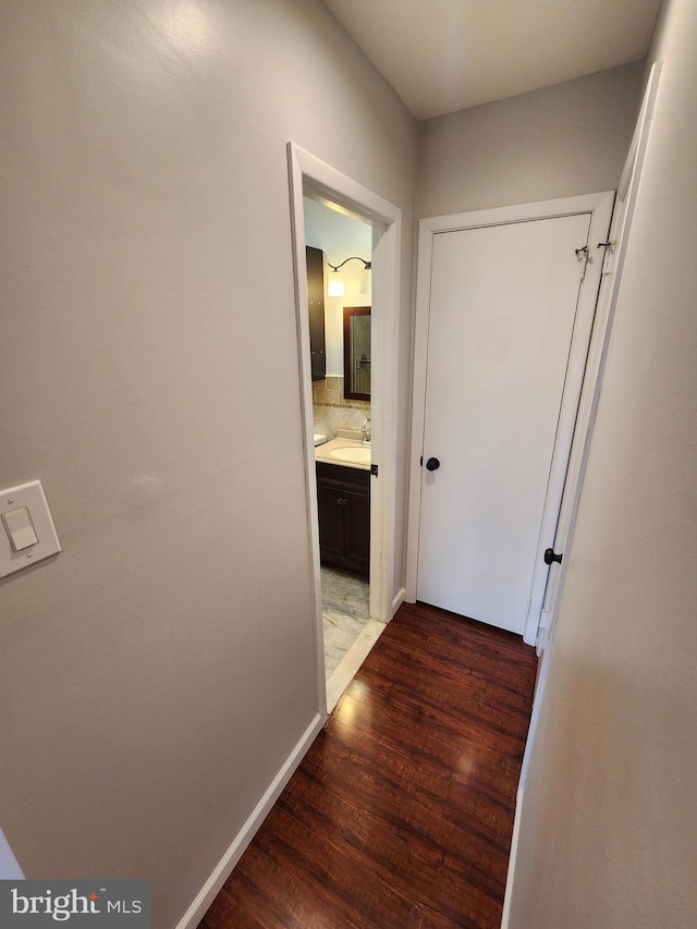 corridor with dark hardwood / wood-style flooring and sink