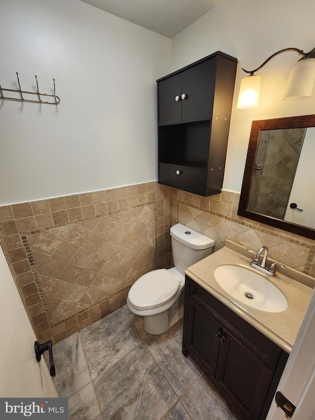 bathroom with tile patterned floors, vanity, toilet, and tile walls