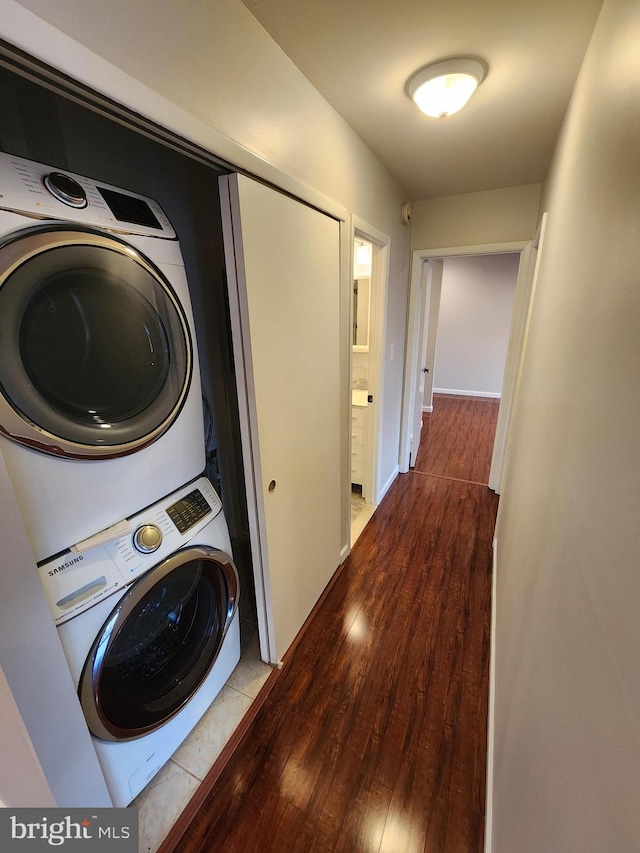 laundry room featuring wood-type flooring and stacked washer and dryer