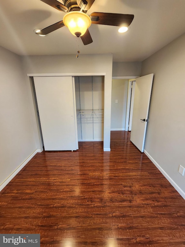 unfurnished bedroom featuring ceiling fan, dark hardwood / wood-style flooring, and a closet