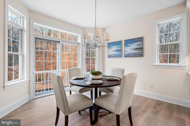 dining space featuring a healthy amount of sunlight, light wood-type flooring, and a chandelier