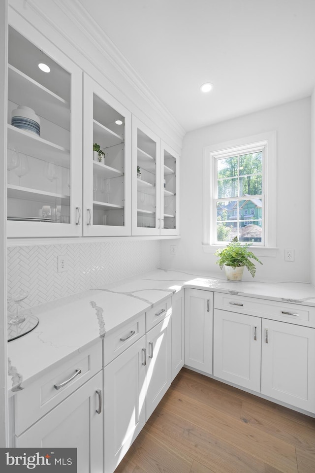 kitchen with white cabinetry, light hardwood / wood-style flooring, and light stone countertops