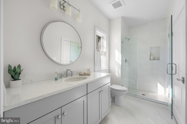 bathroom featuring vanity, a shower with shower door, and toilet