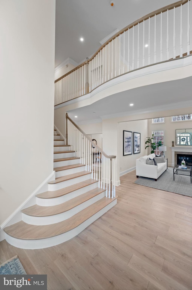 stairs with crown molding, hardwood / wood-style floors, and a towering ceiling