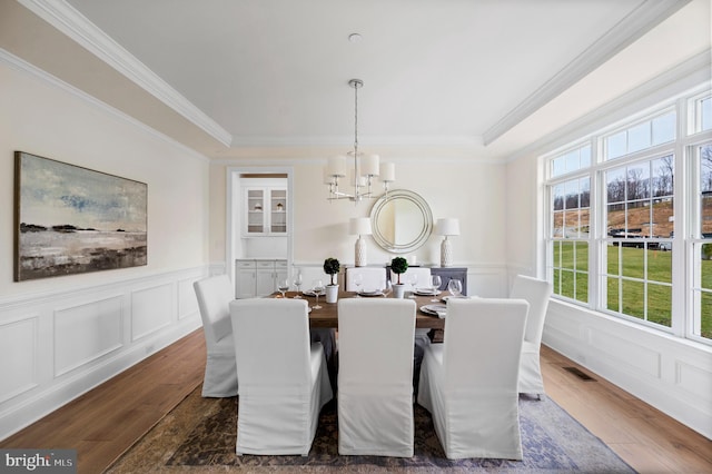 dining room with dark hardwood / wood-style floors, crown molding, and a notable chandelier