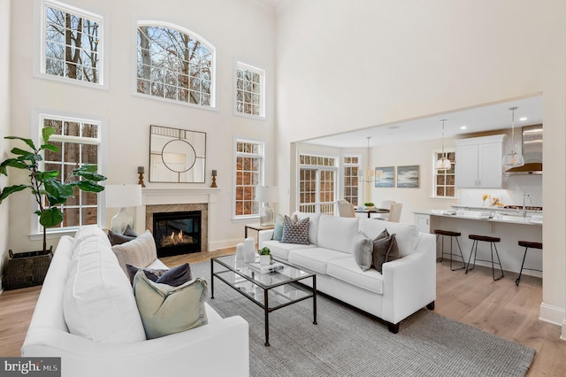 living room with a towering ceiling, light wood-type flooring, and sink