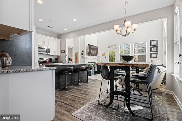 kitchen featuring white cabinetry, dark hardwood / wood-style flooring, stainless steel appliances, and a notable chandelier