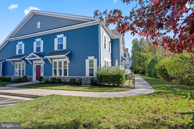 view of front of property with a front yard and central AC unit