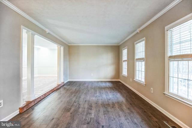 spare room featuring decorative columns, ornamental molding, and dark wood-type flooring