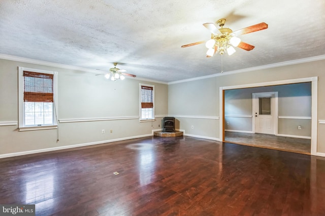 unfurnished living room with a wood stove, dark hardwood / wood-style flooring, ornamental molding, ceiling fan, and a textured ceiling