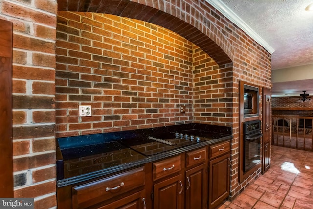 kitchen featuring crown molding, ceiling fan, black appliances, a textured ceiling, and dark stone counters