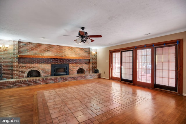 unfurnished living room featuring crown molding, a fireplace, a textured ceiling, and ceiling fan with notable chandelier