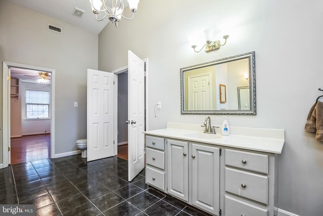 bathroom with vanity, toilet, high vaulted ceiling, and a notable chandelier