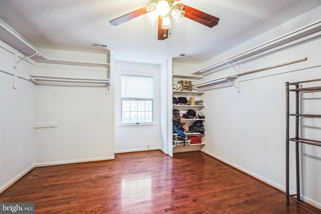 spacious closet with dark wood-type flooring and ceiling fan