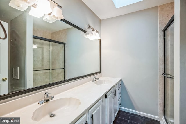 bathroom featuring tile patterned flooring, vanity, a skylight, and a shower with shower door