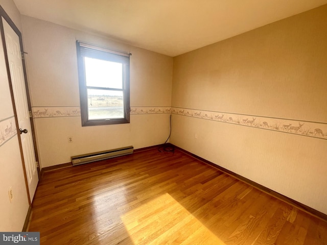 empty room with baseboard heating and hardwood / wood-style floors