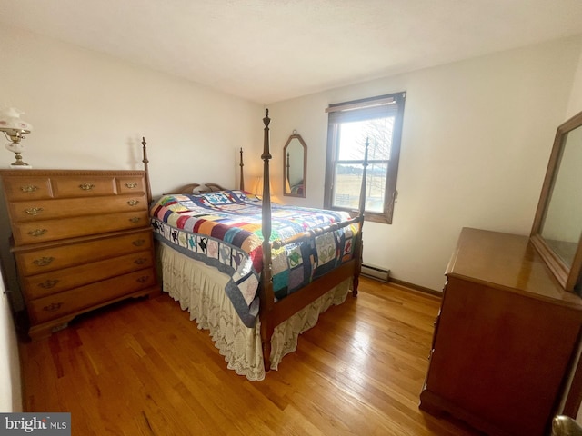 bedroom with baseboard heating and hardwood / wood-style flooring