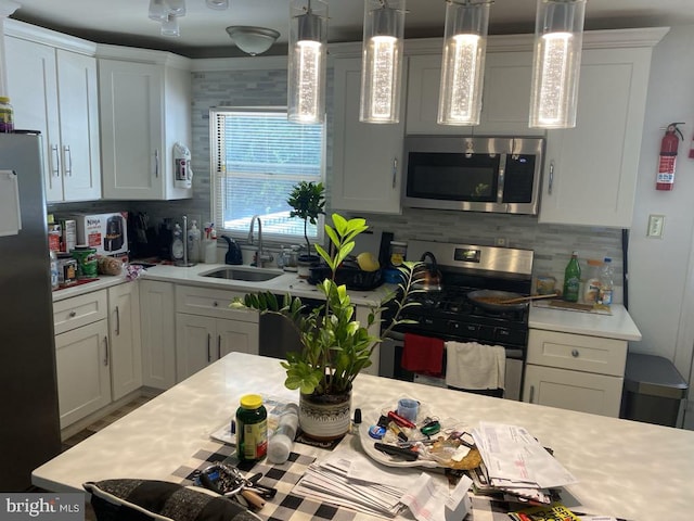 kitchen with hanging light fixtures, white cabinetry, sink, and stainless steel appliances