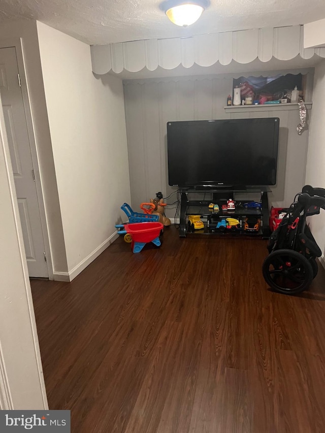 playroom featuring a textured ceiling and dark wood-type flooring