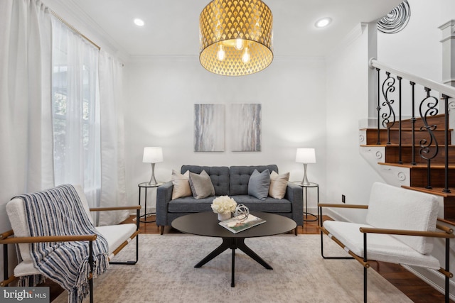 living room featuring light hardwood / wood-style flooring, crown molding, and a notable chandelier