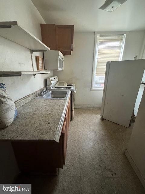 kitchen with stainless steel electric stove, white refrigerator, and sink